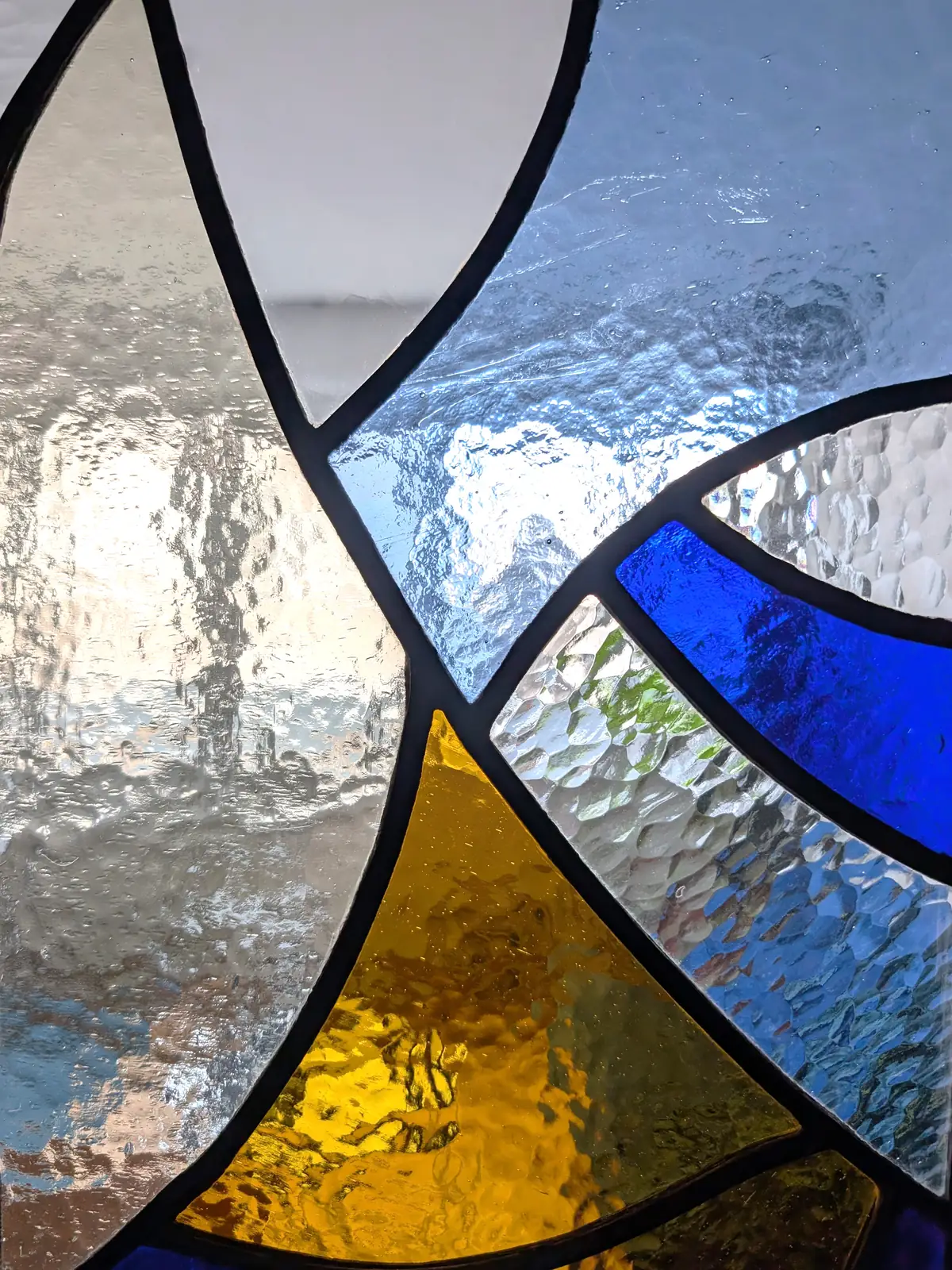 Fragments du ciel, detail of cobalt, amber and textured clear glass pieces joined by dark lead lines