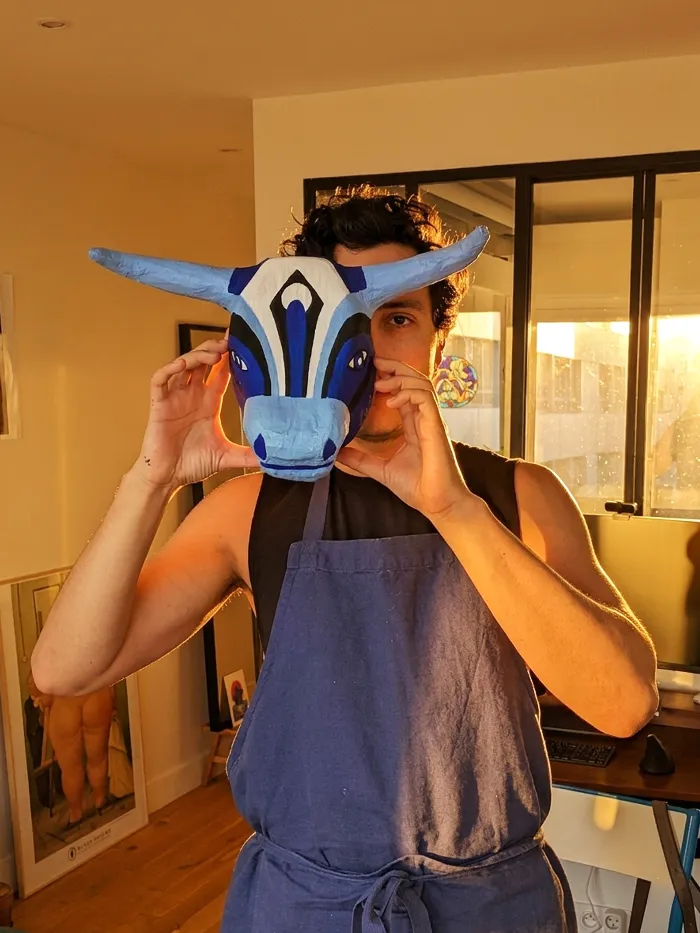 Andrés holding the Toro Azul mask in front of his face at home