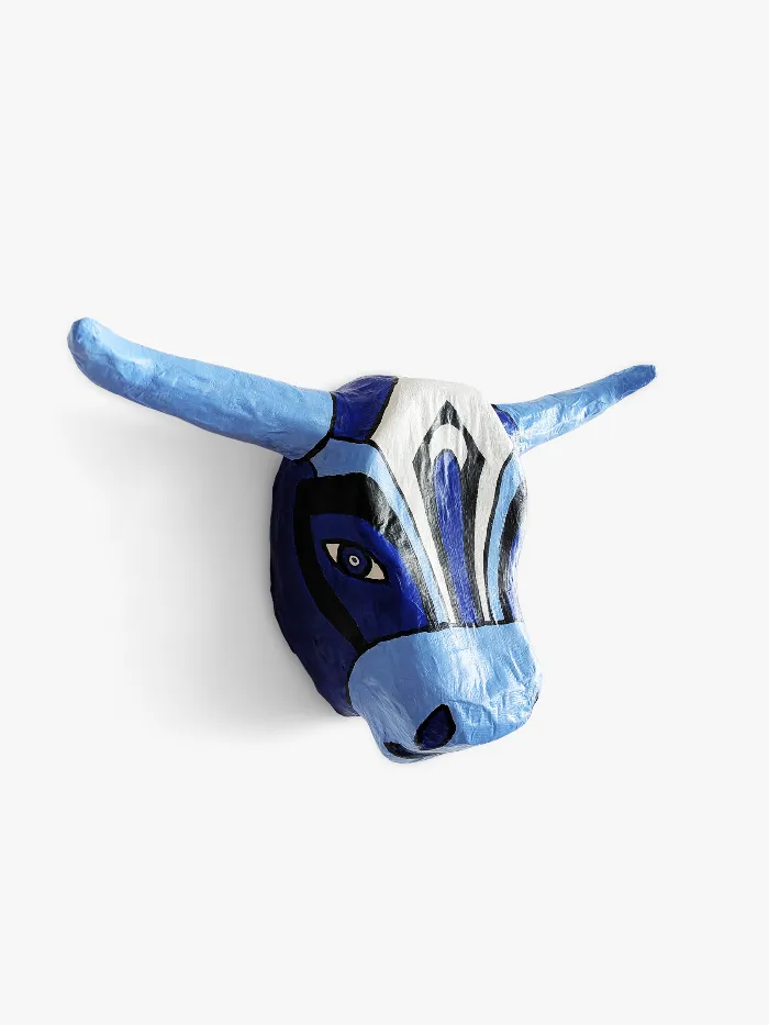 Toro Azul, the painted papier-mâché bull mask seen in three-quarter view against a white wall